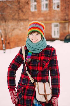 Beautiful smiling woman holding hat in winterの写真素材