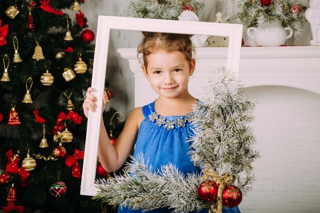 Beautiful chestnut head girl in blue dress looking through the picture frameの写真素材