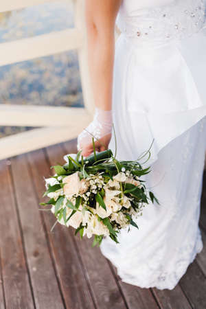 Bride holding beautiful bouquet from roses with pearls in summerの写真素材
