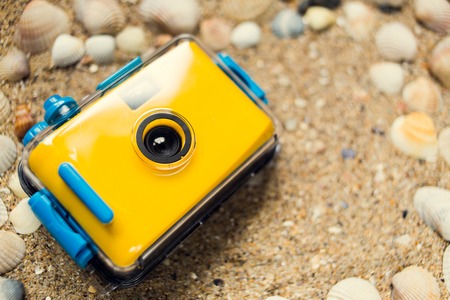 Waterproof camera lying on the sand with seashells, copy spaceの写真素材