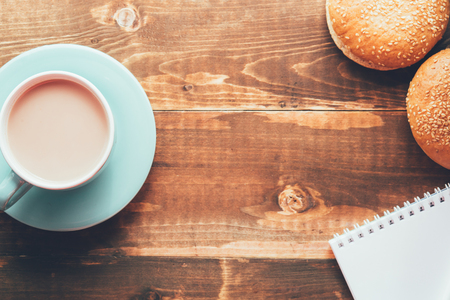 Notebook with cup of coffee on wooden tableの写真素材