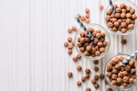 Chocolate corn balls with milk in glasses on white wooden background, top view, copy spaceの写真素材
