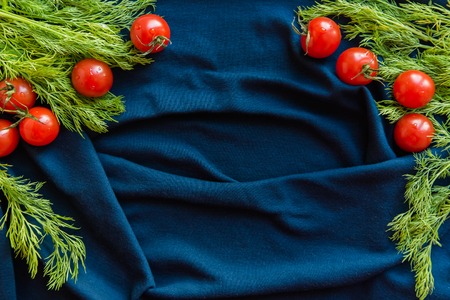 Top view of appetizing cherry tomatoes and dill over blue textile background, copy spaceの写真素材