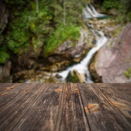 Empty wooden table with summer waterfall background, copy spaceの写真素材