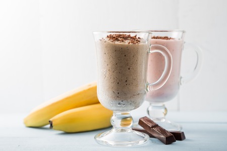 Two smoothies of chocolate, bananas and strawberries, coffee ice-cream cocktails on bright white background, copy spaceの写真素材