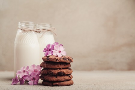 Pile of chocolate chip cookies with two bottles of milk on rustic grey table, copy spaceの写真素材