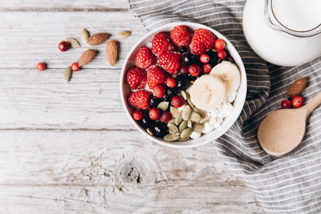Cottage cheese with frozen raspberries, currants, almonds, pumpkin seeds and milk on rustic background. Healthy breakfast concept. Copy spaceの写真素材