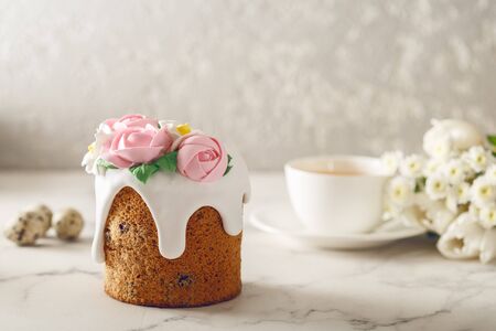 Easter breakfast. Homemade cake with flowing down cream and pink roses on marble table. Cup of tea with flowers. Holiday conceptの写真素材