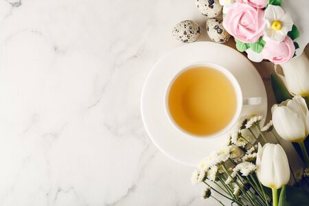 Easter breakfast. Homemade cake with cream roses on marble table. Cup of tea with flowers. Holiday concept. Top view, copy spaceの写真素材