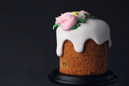 Easter cake with pink creamy roses on wooden black stand on dark grey textured background. Holiday...