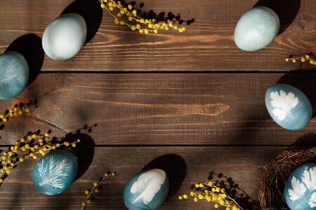 Easter background with white card for text. Eggs on wooden table. Holiday rustic concept. Copy spaceの写真素材