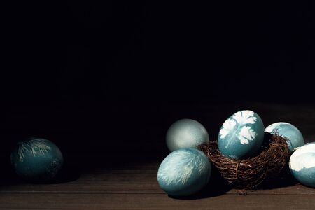Painted blue eggs with printed picture of parsley in nest on wooden table. Easter decoration concept. Top view rustic backgroundの写真素材