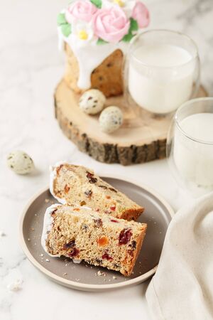 Slices of Easter cake with raisins and dried apricots. Homemade pie with a glass of milk. Piece of cake with marzipan floral decoration on plate. Holiday breakfast and cooking concept.の写真素材