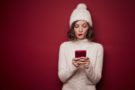 Playful woman in knitted sweater typing in phoneの写真素材
