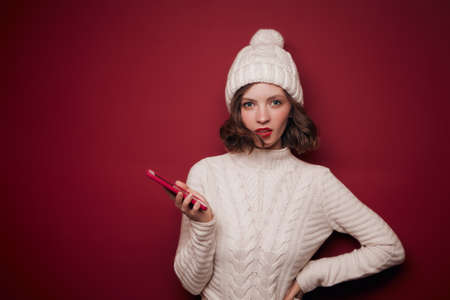 Serious young woman in sweater hold phoneの写真素材