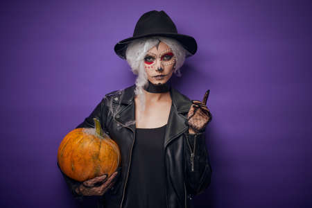 Cheerful young woman in Halloween costume holding pumpkinの写真素材