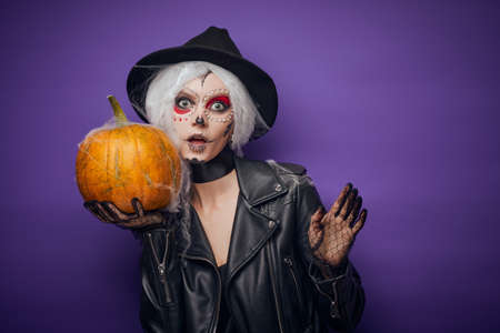 Cheerful young woman in Halloween costume holding pumpkinの写真素材