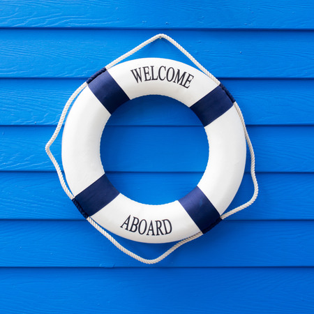 White Life buoy with welcome aboard on blue wall.の写真素材