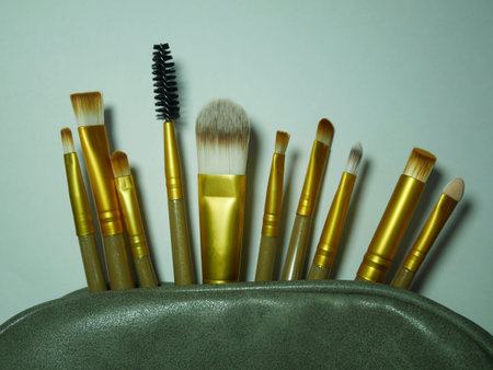 many brown and gold makeup brushes in the green cosmetic bag with the shadow and real white...