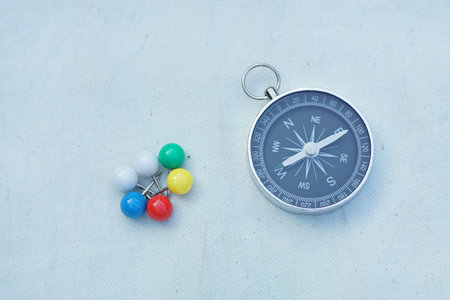 Compass and marking pins on white canvas background, copy space