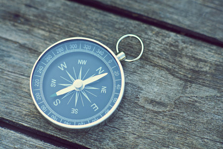 Compass on old wooden table background, journey planning concept, vintage tone
