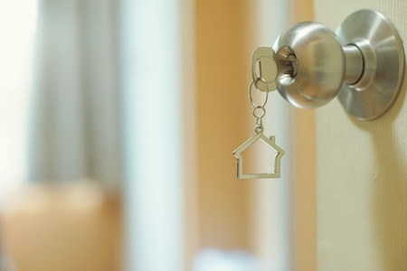 Home key with metal house keyring in keyhole, property concept, copy spaceの写真素材