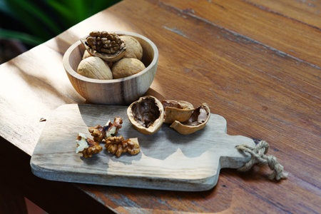 Group of walnuts and a crack nut in wooden bowl on wood background, copy space, super food concept