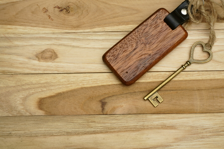 Vintage house key with classic wooden home keyring on wood board background, property concept, copy spaceの写真素材