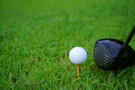 Golf ball and tee with gold course background ready to tee off, copy spaceの写真素材