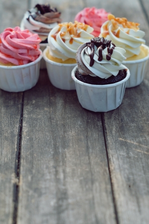 Group of fancy cup cakes, chocolate, caramel and strawberry on wooden table, birthday celebration concept, copy spaceの写真素材
