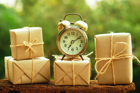 Simple eco friendly gift boxes package wrap with brown paper and vintage clock on wooden table,...