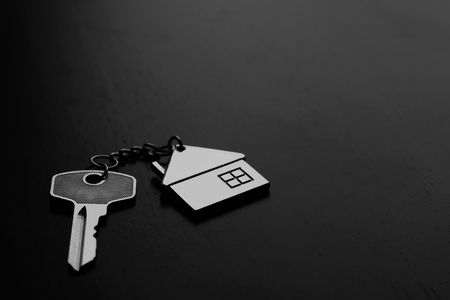 Home key with house keyring on black wood table in dark tone, copy space, real estate conceptの写真素材