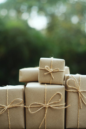 Simple eco friendly gift boxes package wrap with brown paper on wooden table with garden background,...