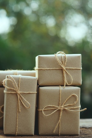 Simple eco friendly gift boxes package wrap with brown paper on wooden table with garden background, green present concept, copy space, earth tone colorの写真素材