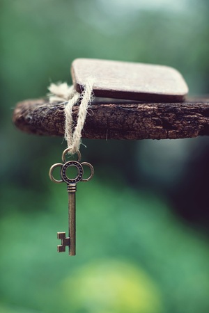 Vintage key with wooden home keyring hanging on old wood plank with blur green garden background, copy space, property conceptの写真素材