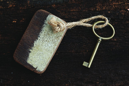 Vintage key with wooden home keyring hanging on old wood plank with blur green garden background, copy space, property conceptの写真素材