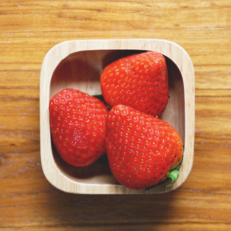 Lovely red fresh ripe strawberry in wood bowl on wooden table, copy spaceの写真素材