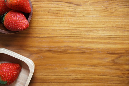 Lovely red fresh ripe strawberry in wood bowl on wooden table, copy space, refreshの写真素材