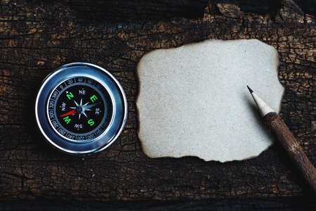 Compass, burnt brown paper and wooden pencil on crumples paper background, vintage tone, journey planning concept, copy space, blank space, top viewの写真素材
