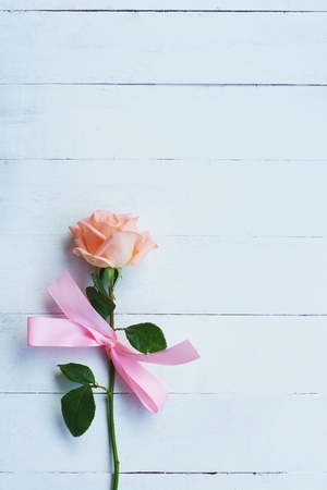 Lovely soft orange pink color rose tied by pink ribbon and brown gift box on white wood table background, sweet valentine present concept, copy spaceの写真素材