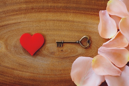Red mini heart textile, white and pink petal of rose and heart shape key on wooden table, valentine love concept, copy spaceの写真素材