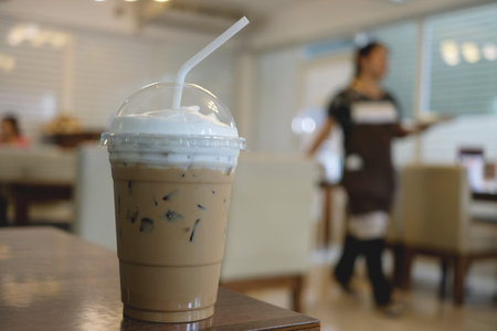 Cup of ice milk coffee on wooden table in a cafe, copy space