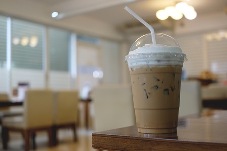 Cup of ice milk coffee on wooden table in a cafe, copy spaceの写真素材