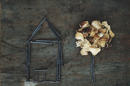 House made of nail and little tree made of wood dust on old wood background, creative artwork conceptの写真素材
