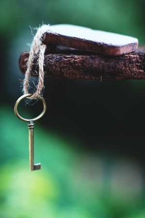 Vintage key with wooden home keyring hanging on old wood plank with blur green garden background, copy space, property conceptの写真素材