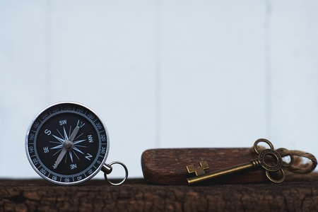 Compass and vintage key on clear white wooden wall background, vintage tone, journey planning concept, blank space, top view, copy spaceの写真素材