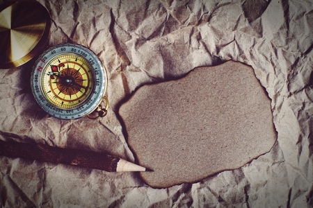 Compass, burnt brown paper and wooden pencil on crumples paper background, vintage tone, journey planning concept, blank space, top view, copy spaceの写真素材