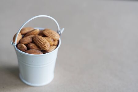 Almond nut in white can and green leaf on wooden table background, copy spaceの写真素材