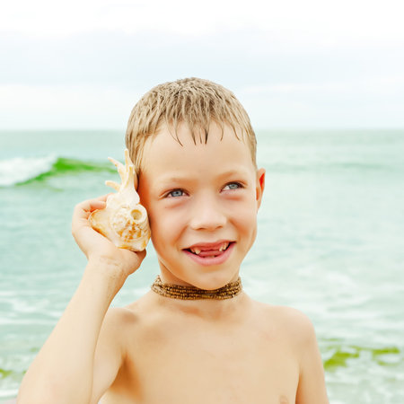 boy with shell on the ocean beach