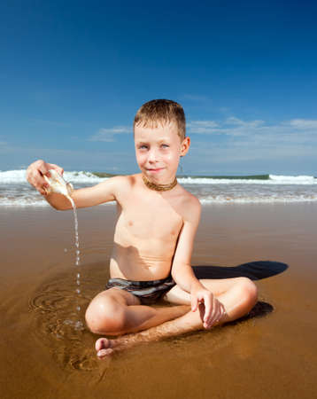 boy with shell on the ocean beachの写真素材